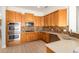 A kitchen with stainless steel double oven, gas cooktop, wood cabinets, and tile backsplash at 21406 E Mewes N Rd, Queen Creek, AZ 85142