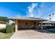 Tan brick ranch home with carport, landscaping, and a blue sky at 10104 W Forrester Dr, Sun City, AZ 85351