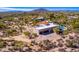 Aerial view of a luxurious home with a pool, desert landscaping, and mountain views at 9446 E Romping Rd, Carefree, AZ 85377