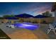 Illuminated pool with blue umbrellas, lounge chairs, and a water feature at 30807 N 117Th Dr, Peoria, AZ 85383