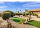 Spacious backyard with a covered patio, artificial turf, a fire pit, and desert landscaping at 13215 W La Terraza Dr, Sun City West, AZ 85375