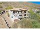 Luxury home with stone accents, balconies, and a paved driveway nestled in the mountains at 11328 E Dreyfus Ave, Scottsdale, AZ 85259