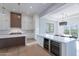 Modern white kitchen with island, wine fridge, and open dining area at 11328 E Dreyfus Ave, Scottsdale, AZ 85259