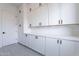 Bright laundry room with ample white cabinets, countertop space, and patterned tile at 11328 E Dreyfus Ave, Scottsdale, AZ 85259