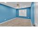 Blue bedroom with ceiling fan, window with shutters, and wood-look tile flooring at 43558 W Harris Dr, Maricopa, AZ 85138