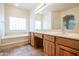 Bright bathroom with double sinks, soaking tub, and large mirror at 16068 W Edgemont Ave, Goodyear, AZ 85395