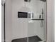 Modern shower with white geometric tile, black accents, glass door, and hexagon floor tiles at 3335 E San Angelo Ave, Gilbert, AZ 85234