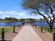 Community lake with a walking path, shaded sitting area, and a pier at 37028 W Prado St, Maricopa, AZ 85138