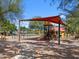 Playground with swings, slides, and shade structure in community park at 37374 W San Clemente St, Maricopa, AZ 85138