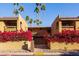 Exterior view of condo building with Spanish-style roof, palm trees, and lush bougainvillea at 8500 E Indian School Rd # 129, Scottsdale, AZ 85251