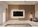 Main bedroom showcasing a marble-framed TV mounted on a wood-paneled wall and a sitting chair at 14521 E Corrine Dr, Scottsdale, AZ 85259