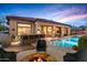 Resort-style backyard with pool, spa, fire pit, and outdoor kitchen at sunset at 36701 N Porta Nuova Rd, Scottsdale, AZ 85262