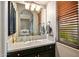 Bathroom vanity with single sink, dark wood cabinets, arched mirror, and window with wood blinds at 36701 N Porta Nuova Rd, Scottsdale, AZ 85262