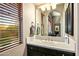Bathroom vanity with single sink, dark wood cabinets, and window with wood blinds at 36701 N Porta Nuova Rd, Scottsdale, AZ 85262