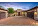 Home exterior with three-car garage, stone archway, and desert landscaping at dusk at 36701 N Porta Nuova Rd, Scottsdale, AZ 85262