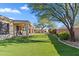 Backyard with covered patio, built-in fireplace, artificial turf, and desert landscaping at 1613 W Ainsworth Dr, Anthem, AZ 85086