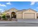 Beige stucco home with arched entryway, three-car garage, and desert landscaping at 1613 W Ainsworth Dr, Anthem, AZ 85086