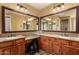 Main bathroom with dual vanities, large mirrors, and wood cabinetry at 19409 W Pasadena Ave, Litchfield Park, AZ 85340