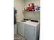 Laundry room with white washer and dryer and built-in shelving at 8506 S 256Th Dr, Buckeye, AZ 85326