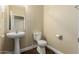 Half bathroom with pedestal sink, toilet, and wood-look tile flooring at 15835 W Desert Mirage Dr, Surprise, AZ 85379