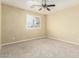 Empty bedroom with ceiling fan, carpeted floors, and a large window at 15835 W Desert Mirage Dr, Surprise, AZ 85379