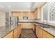 Bright kitchen with wood cabinetry, granite countertops, and stainless steel sink at 15835 W Desert Mirage Dr, Surprise, AZ 85379