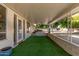 Covered back patio with artificial turf and views of the surrounding trees at 10330 W Desert Forest Cir, Sun City, AZ 85351