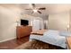Spacious bedroom with ceiling fan, wood dresser, hardwood floors, and attached closet at 10330 W Desert Forest Cir, Sun City, AZ 85351