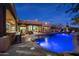 Night view of a pool with rock features and an outdoor kitchen area at 33296 N Vanishing Trl, Scottsdale, AZ 85266