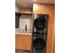 Laundry room with a stacked washer and dryer and wood cabinetry at 8702 E Silver Saddle Dr, Carefree, AZ 85377