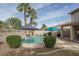 In-ground pool with rock waterfall feature, surrounded by palm trees, green shrubs, and a covered patio at 912 N 164Th Dr, Goodyear, AZ 85338