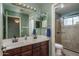 Bathroom with double sinks, brown cabinets, and a glass shower enclosure at 912 N 164Th Dr, Goodyear, AZ 85338