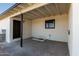 Covered backyard patio with concrete floor, dark brown door, and window at 1430 W Maddock Rd, Phoenix, AZ 85086
