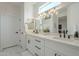 Spacious double vanity bathroom with white shaker cabinets, marble tile, and modern light fixture at 15720 W Goldenrod Dr, Surprise, AZ 85374