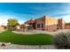 Backyard view of the single story home, patio, landscaping, and green grass at 4314 W Saguaro Park Ln, Glendale, AZ 85310