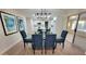 Dining area with a modern light fixture, a glass-top table, and blue upholstered chairs at 4636 E Florian Ave, Mesa, AZ 85206