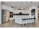 Modern white kitchen with stainless steel appliances, large island with seating, and dark wood-look tile floors at 4711 N 212Th Dr, Buckeye, AZ 85396