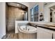 Main bathroom with a soaking tub, walk-in shower, and plantation shutters at 4711 N 212Th Dr, Buckeye, AZ 85396