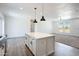 A kitchen island with white cabinets, a quartz countertop, pendant lighting, and wood-style flooring at 51937 W Wildwood Rd, Maricopa, AZ 85139