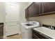 Laundry room with dark wood cabinets, granite countertops, and white appliances at 8146 E Wingspan Way, Scottsdale, AZ 85255