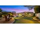 Landscaped backyard with putting green, lighting, and palm trees at dusk at 21057 N 74Th Way, Scottsdale, AZ 85255