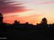 Residential homes silhouetted against a vibrant sunset at 9190 W Wenden Dr, Arizona City, AZ 85123