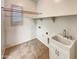 Bright laundry room with utility sink, built-in shelving, and window at 10559 E Simone Ave, Mesa, AZ 85212