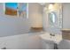 Small bathroom with pedestal sink, decorative mirror, and a window for natural light at 10015 N 14Th St # 7, Phoenix, AZ 85020