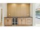 Wet bar with dark countertop, wine cooler, and light wood cabinets at 10587 E Caron St, Scottsdale, AZ 85258