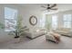 Bright living room with white couches, a ceiling fan, and large windows at 4510 N Pierce Ct, Buckeye, AZ 85396