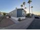 Gray manufactured home with a deck and carport, landscaped yard, and palm trees at 821 W Kachina Trl, Phoenix, AZ 85040