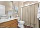 Clean bathroom with wood vanity and striped shower curtain at 17395 W Straight Arrow Ln, Surprise, AZ 85387