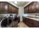 Laundry room with matching dark wood cabinets and modern appliances at 10742 E Greythorn Dr, Scottsdale, AZ 85262