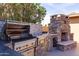 Outdoor kitchen with built-in grill and stone fireplace at 10801 N 45Th St, Phoenix, AZ 85028